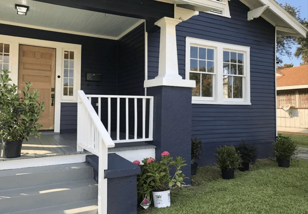Beautifully painted navy blue home with white trim and a natural wood door, expertly refinished by The Exterior Zone in Metamora, MI.